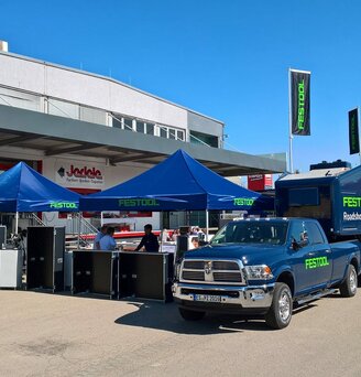 3x3m blue event gazebo customised with green Festool logo combined with company van and caravan in front of DIY shop Jedele