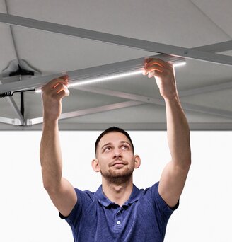 The man attaches the LED strips to the folding gazebo.